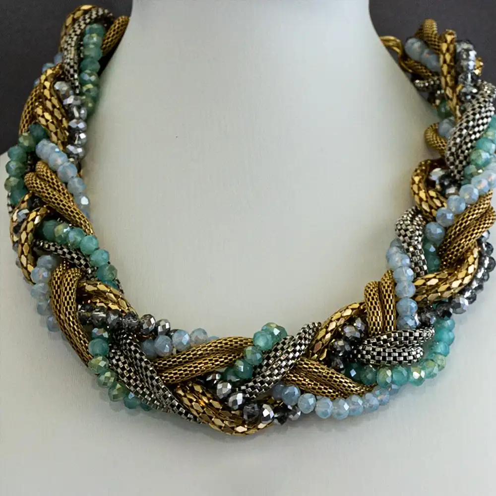 Closeup of a statement necklace features six strands artfully intertwined into one dynamic design. Combining two polished gold-tone strands, one sleek silver strand, and three shimmering strands of faceted glass