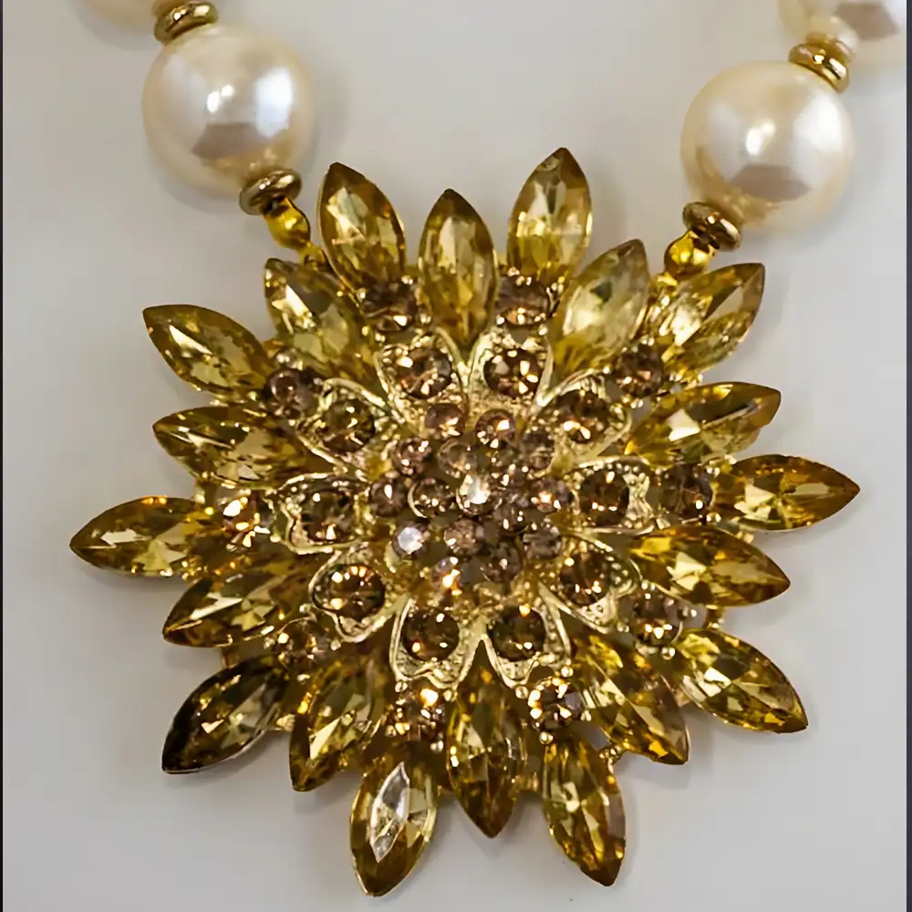 Closeup of a necklace showcases a new 2.75-inch statement pendant, dazzling with light gold rhinestones in a variety of dynamic shapes and sizes.