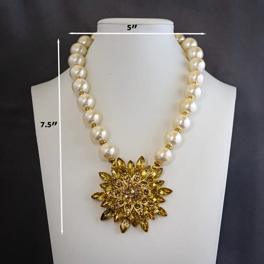 Dimensions of a necklace showcases a new 2.75-inch statement pendant, dazzling with light gold rhinestones in a variety of dynamic shapes and sizes.