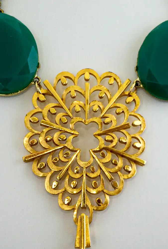 Close up of a elegant vintage necklace features graduated green chalcedony stones set in subtle gold tone settings,