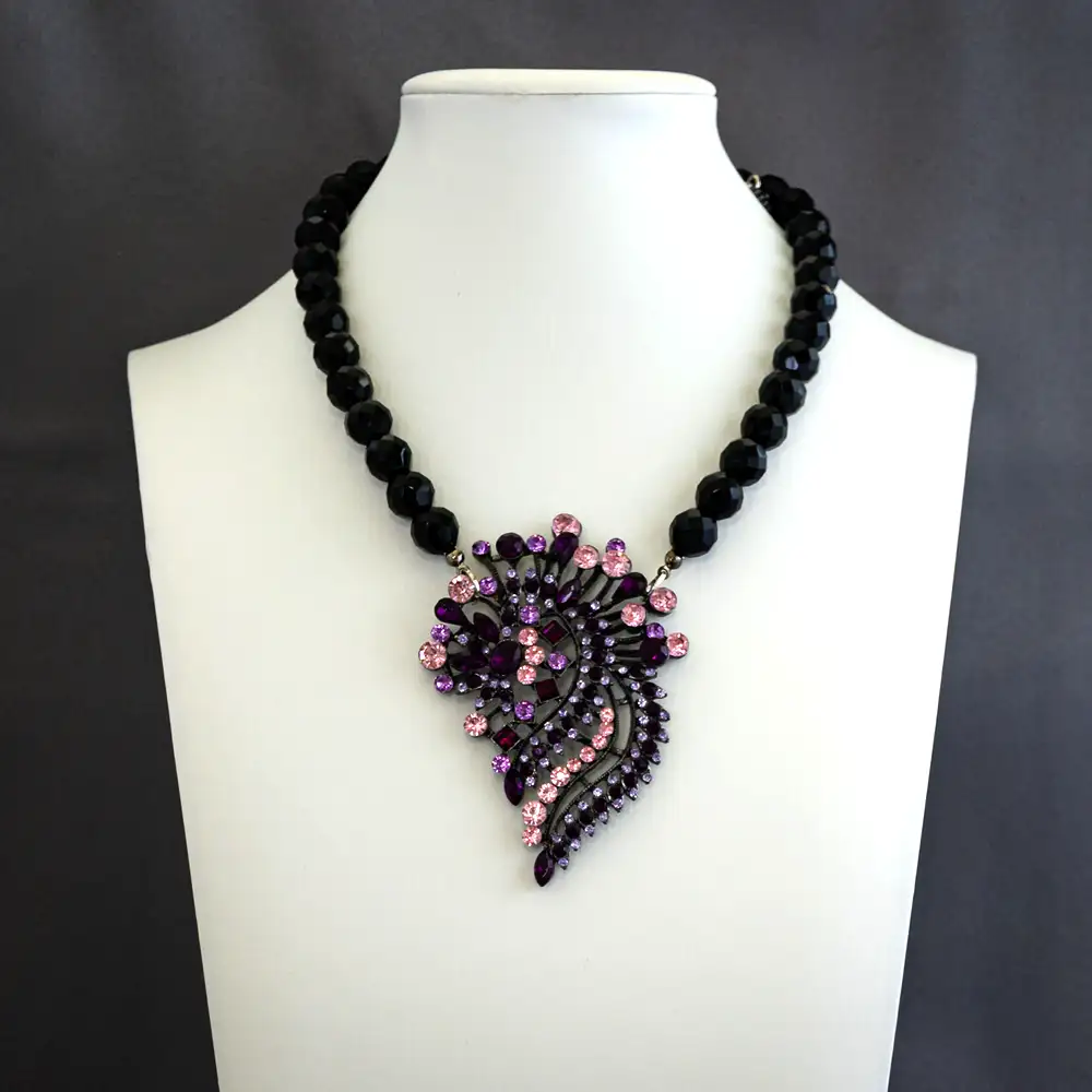 vintage necklace features a dramatic 2.25" by 3.25" pendant, brilliantly adorned with bright pink, dark purple, and lavender rhinestones.