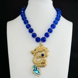 A striking vintage gold-tone dragon pendant takes center stage, detailed with a brilliant cobalt blue rhinestone and enamel inlays in deep cobalt and vibrant teal.