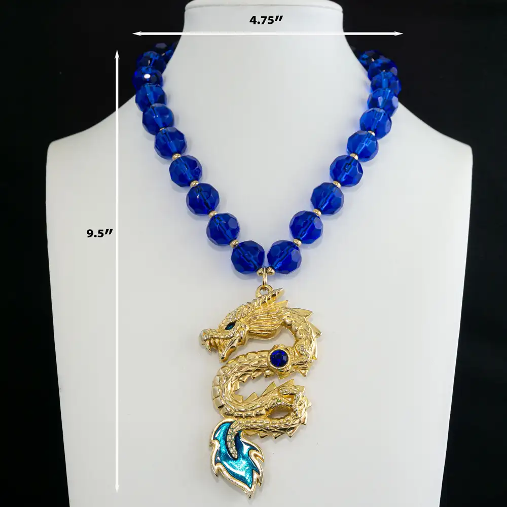 Description of A striking vintage gold-tone dragon pendant takes center stage, detailed with a brilliant cobalt blue rhinestone and enamel inlays in deep cobalt and vibrant teal.