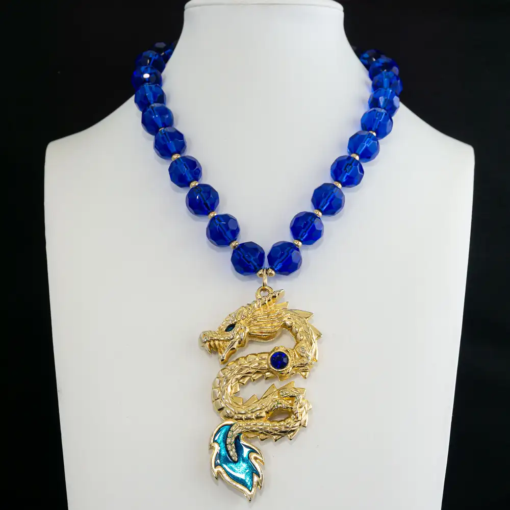 A striking vintage gold-tone dragon pendant takes center stage, detailed with a brilliant cobalt blue rhinestone and enamel inlays in deep cobalt and vibrant teal.