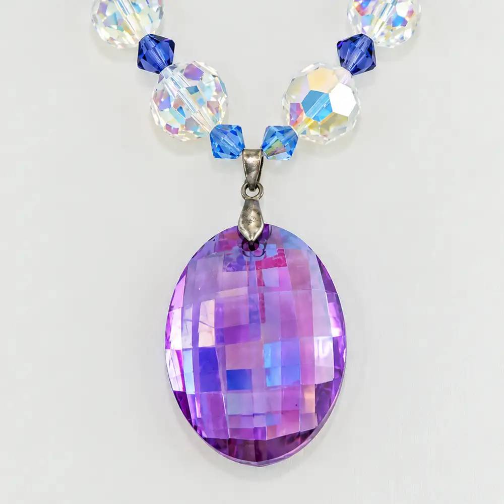 Close up of A sparkling strand of vintage faceted crystal beads of 6mm, 10mm and 12mm features a mesmerizing blend of blue, green, purple, and clear hues.