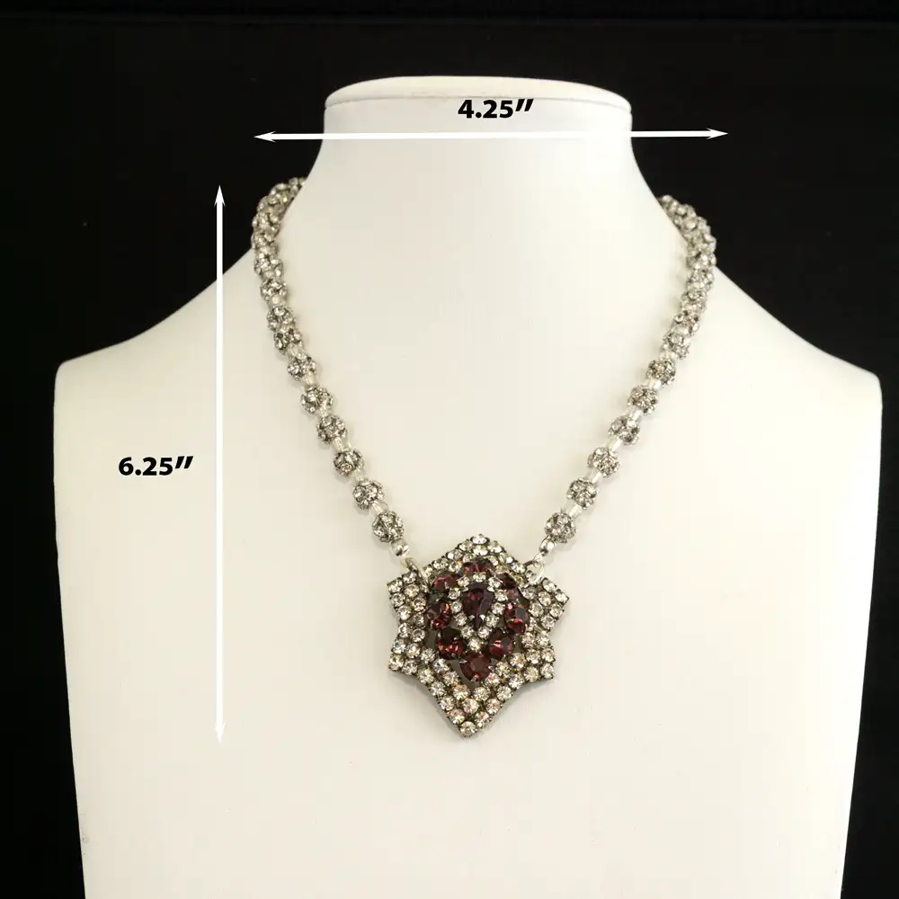 A vintage slight six-point star pendant, adorned with vibrant raspberry and clear rhinestones, serves as the captivating centerpiece.