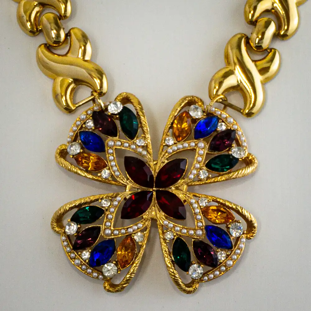 Close up of statement necklace centers on a brilliant 2.375” round pendant adorned with multi-colored rhinestones and delicate faux seed pearls.
