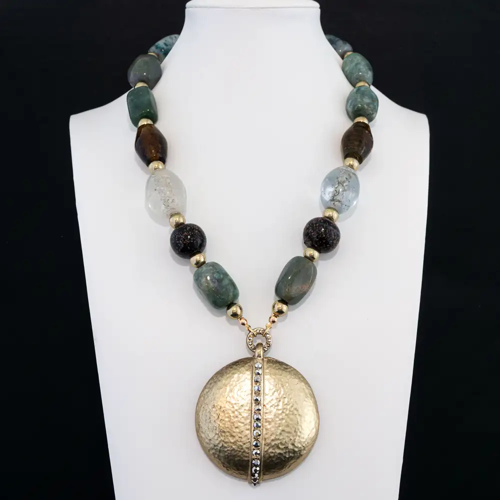 This striking statement necklace features an eclectic strand of variegated green, amber, clear, and speckled glass beads separated by gold-tone spacers.