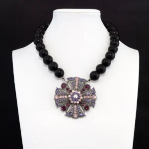 statement necklace features a strand of smooth, high-gloss black beads that beautifully frame an ornate, filigree-style metal pendant