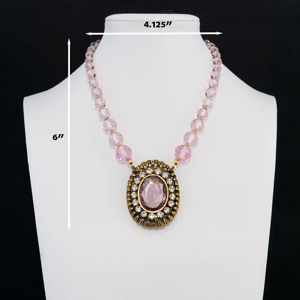 Description of a romantic statement necklace features a strand of faceted light pink glass beads that reflect a soft, luminous sparkle.