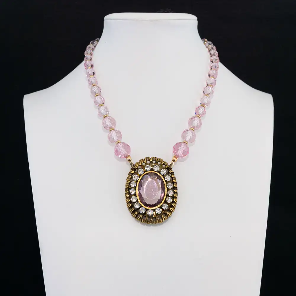 a romantic statement necklace features a strand of faceted light pink glass beads that reflect a soft, luminous sparkle.