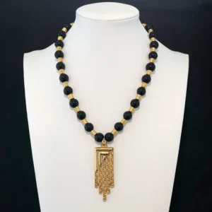 This striking vintage necklace features glossy black round beads alternating with textured gold-tone spacers.