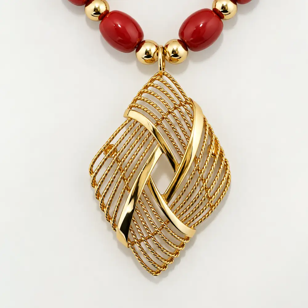 close up of a bold vintage necklace showcases vibrant red oval beads separated by polished gold-tone accent beads.