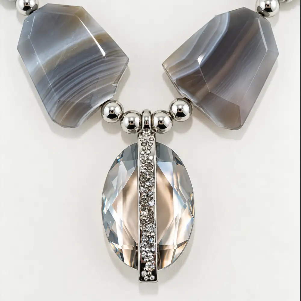 Close up of a striking necklace features large, organic slabs of natural grey and white banded agate separated by polished silver-tone accent beads.