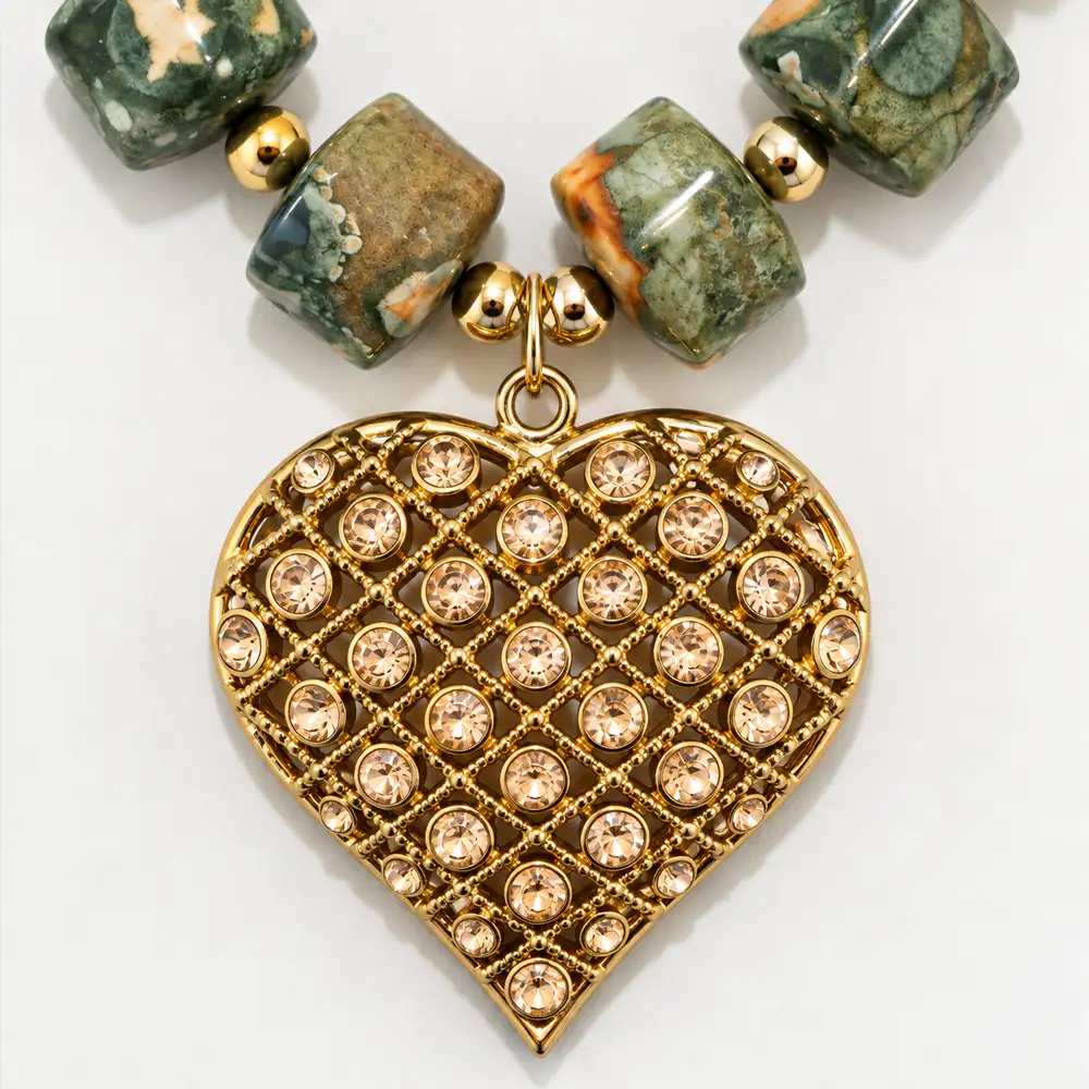Close up of a bold necklace features natural, barrel-shaped leopard skin jasper beads in earthy green and peach tones, accented by small gold spacers.