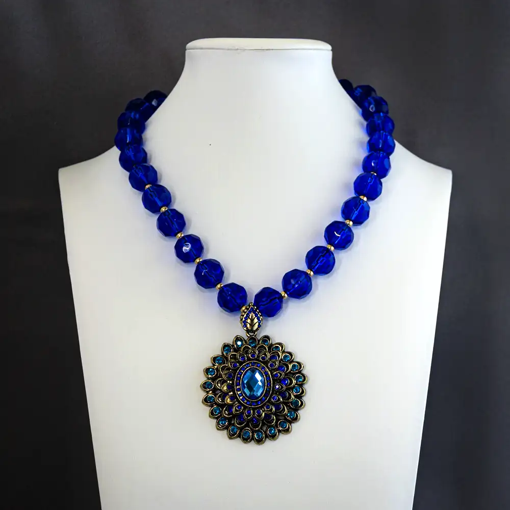 a 2-inch round vintage pendant, this 16-inch necklace features radiant cobalt and teal rhinestones nestled in antiqued gold settings.