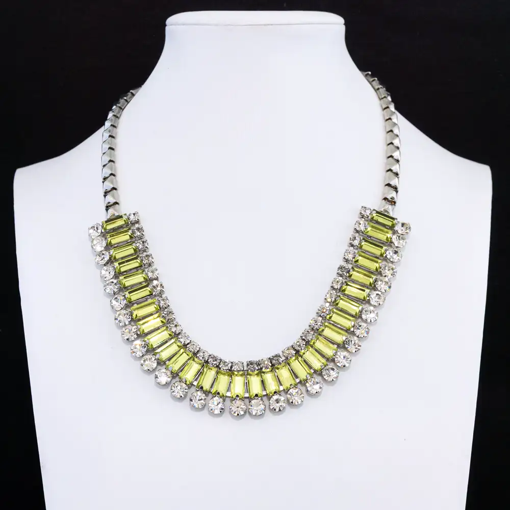 This dazzling vintage statement necklace features a striking band of baguette-cut, peridot-green rhinestones set in a silver-tone frame.