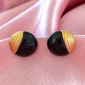 bold vintage clip-on earrings feature smooth, black dome cabochons elegantly paired with ribbed, fan-like gold-toned metal accents