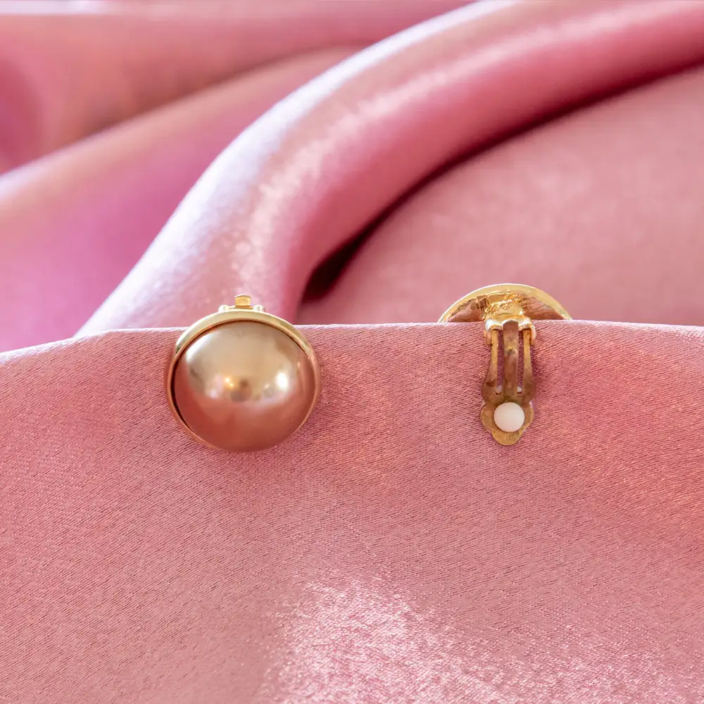 elegant clip-on earrings feature smooth, 0.75-inch diameter faux glass pearls set in a polished gold-toned bezel.