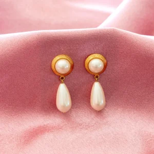 elegant drop earrings feature a textured gold-toned button stud holding a round faux pearl